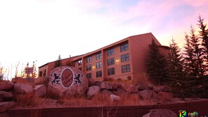 A building with a large rock sign in front, surrounded by rocks and trees. - Brian Head Royal Prince Suite, Pool & Jacuzzi, Ski-I/O, 3 BR +, 2 Bath, Sleep 14 (Brian Head)