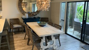 A dining area with a large table, wicker chairs, a blue cabinet, and a decorative mirror.
