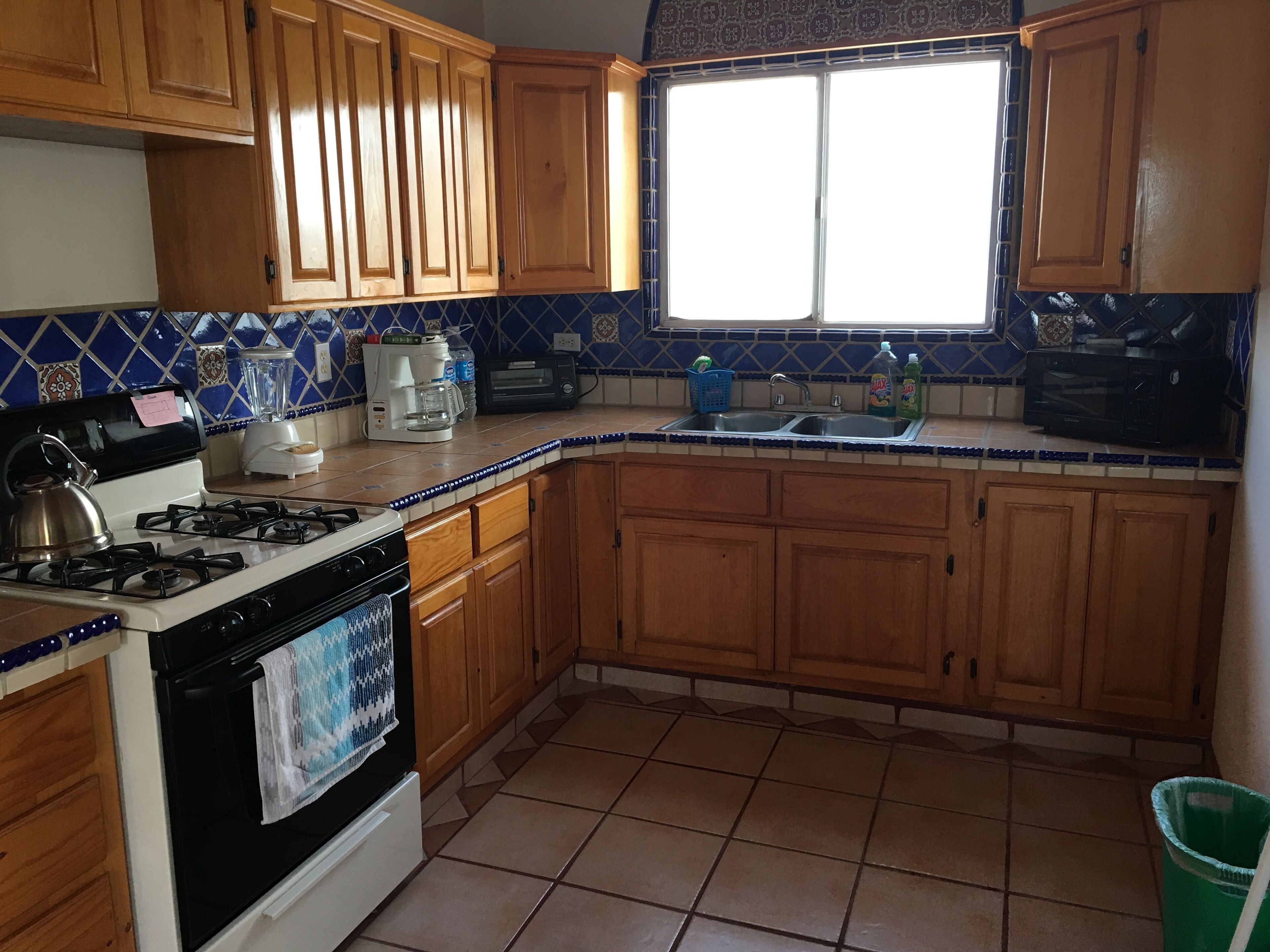A kitchen with wooden cabinets, a gas stove, a microwave, and a window with a view.