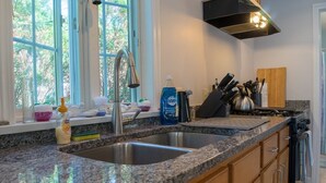 Eine Küche mit Granit-Arbeitsplatten, Spüle aus Edelstahl und Holzschränken.