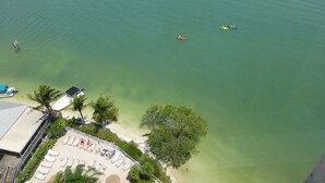 An aerial view of a beach with clear waters, a few boats, and a resort area with sun loungers and umbrellas. - Lovers Key Resort, Luxury Top Floor Penthouse with Best Views in the Resort (Fort Myers Beach)