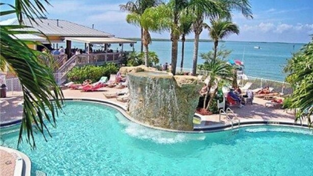 A pool with a rock feature, lounge chairs, and a view of the ocean. - Lovers Key Resort, Luxury Top Floor Penthouse with Best Views in the Resort (Fort Myers Beach)