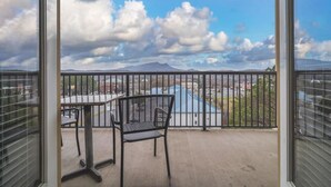 A balcony with a table and chairs, offering a view of a town and mountains. - Base Camp - Unit 1305 - Mountain View Condos - FREE Attraction Ticket with EACH night Stay Including Dollywood (Pigeon Forge)