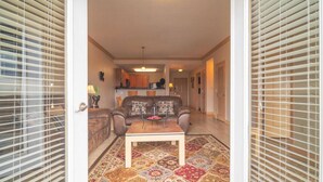 A living room with a sofa, coffee table, and patterned rug. There is a kitchen in the background with cabinets and a countertop. - Base Camp - Unit 1305 - Mountain View Condos - FREE Attraction Ticket with EACH night Stay Including Dollywood (Pigeon Forge)