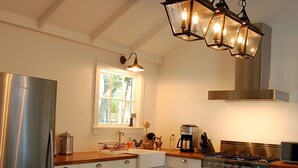 Eine Küche mit einem Edelstahl-Kühlschrank, einem Herd und einem Fenster über der Spüle.