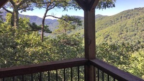 Un mirador de madera con vistas a una cadena montañosa boscosa.
