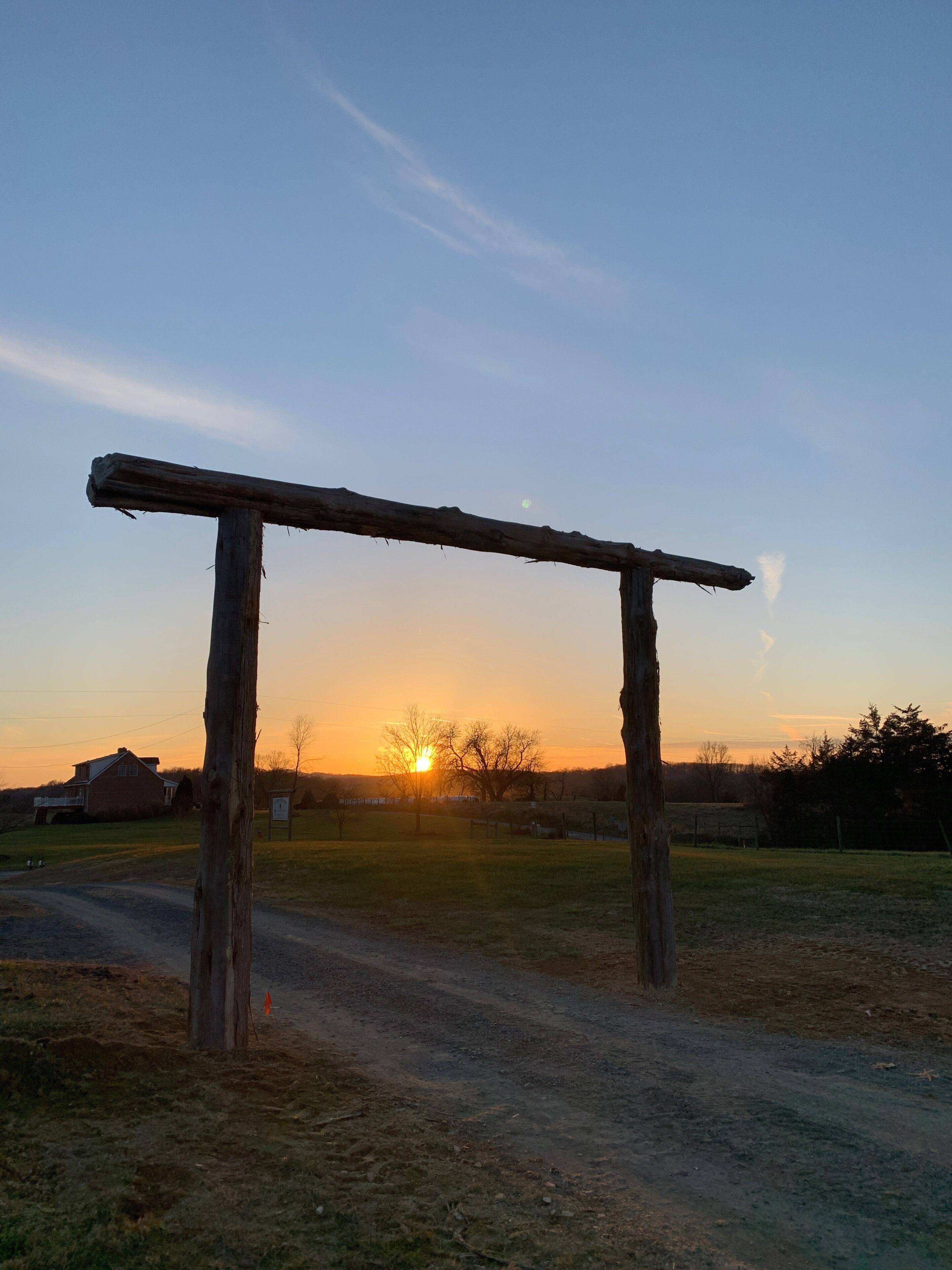 A rustic wooden structure in a rural setting with a sunset in the background.
