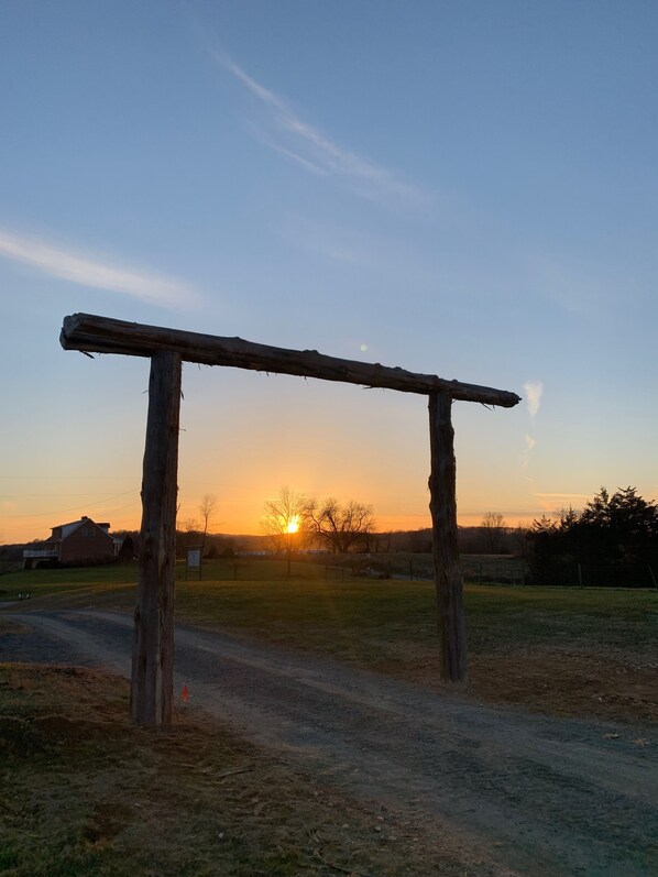 A rustic wooden structure in a rural setting with a sunset in the background.