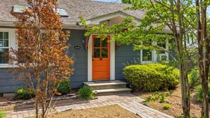 A house with a bright orange front door, a mailbox, and a number 6340 on the door.