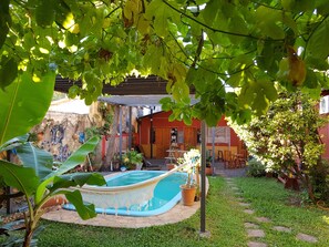 A pool area with a hammock, surrounded by greenery and a mural on the wall. - El Nomada Hotel & Hostel (Asunción)