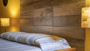 A bed with striped bedding, a wooden headboard, and two wall-mounted lamps. - El Nomada Hotel & Hostel (Asunción)