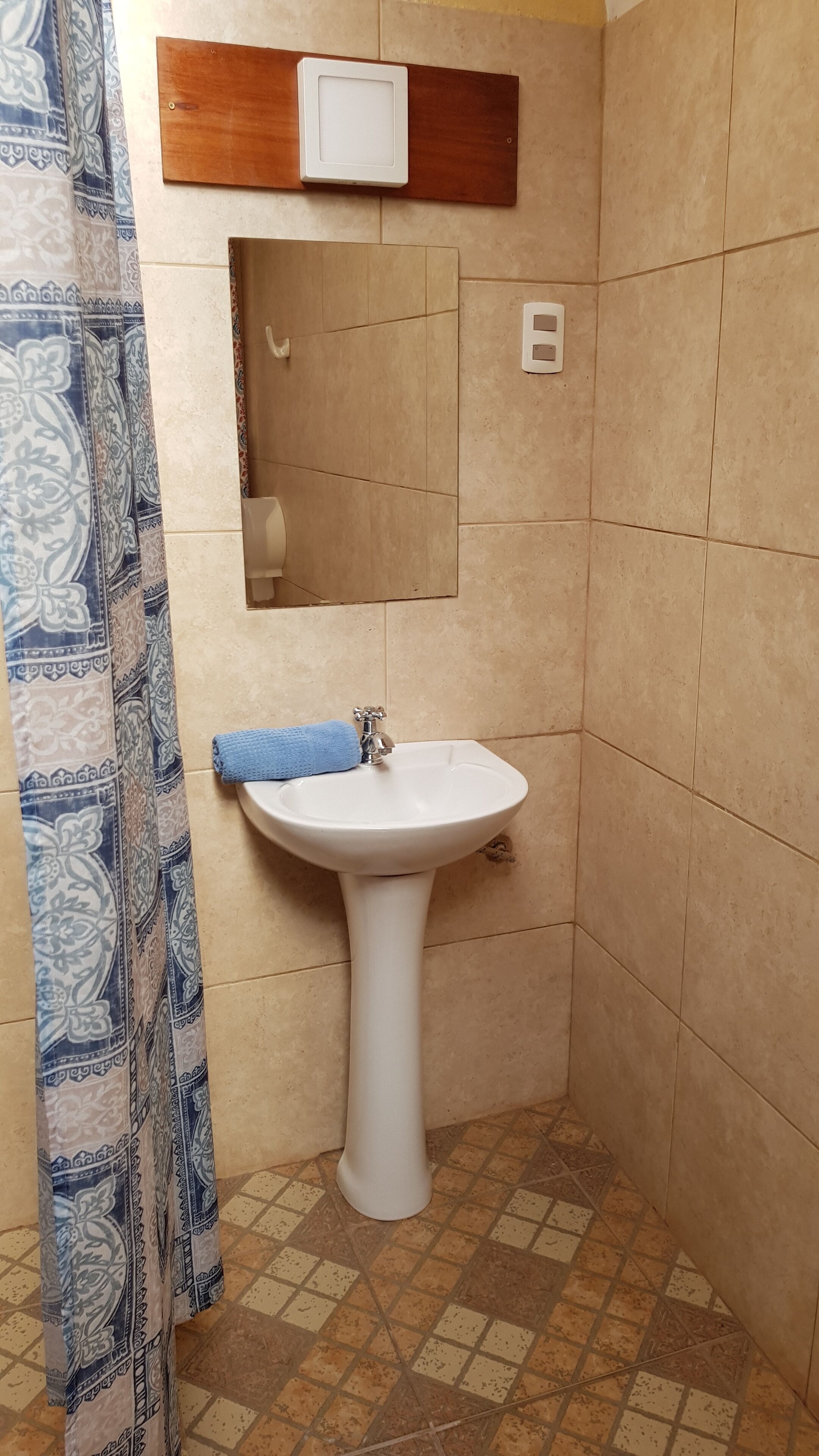 A bathroom with a white pedestal sink, a mirror, and a towel hanging on the wall.