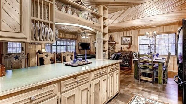 A spacious kitchen with wooden cabinets, a large island, and a dining area with rustic chairs.