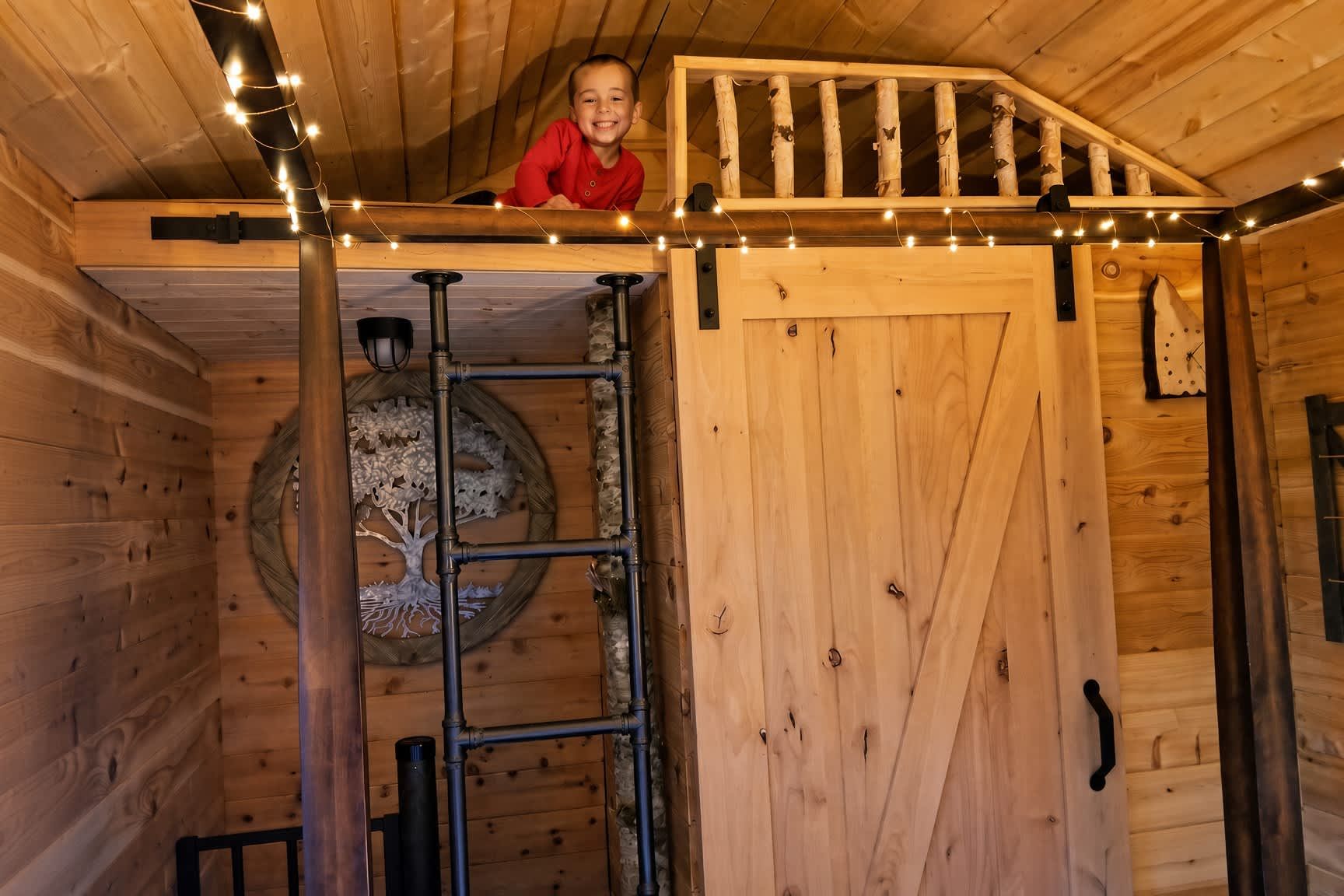 Un intérieur en bois avec une mezzanine, une échelle et un arbre décoratif.