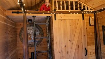 Un intérieur en bois avec une mezzanine, une échelle et un arbre décoratif.