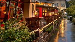 Un restaurante con terraza, un letrero que indica que sirve cerveza y vino locales, y una panadería.