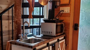 A compact kitchen with a sink, a microwave, and hanging pots. - Treehouse Place at Deer Ridge Featured top 10 USA (Snohomish)