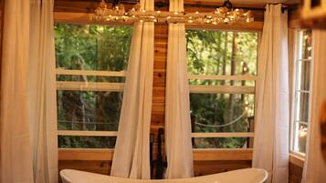 Ein Holzblock-Interieur mit großem Fenster, Vorhängen und einer Badewanne.