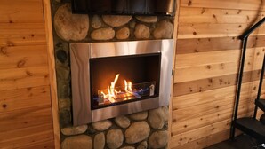 A stone fireplace with a metal front and a television mounted above it. - Treehouse Place at Deer Ridge Featured top 10 USA (Snohomish)