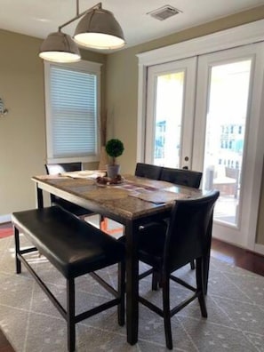 Un comedor con una mesa rectangular, sillas negras, un banco e iluminación colgante.