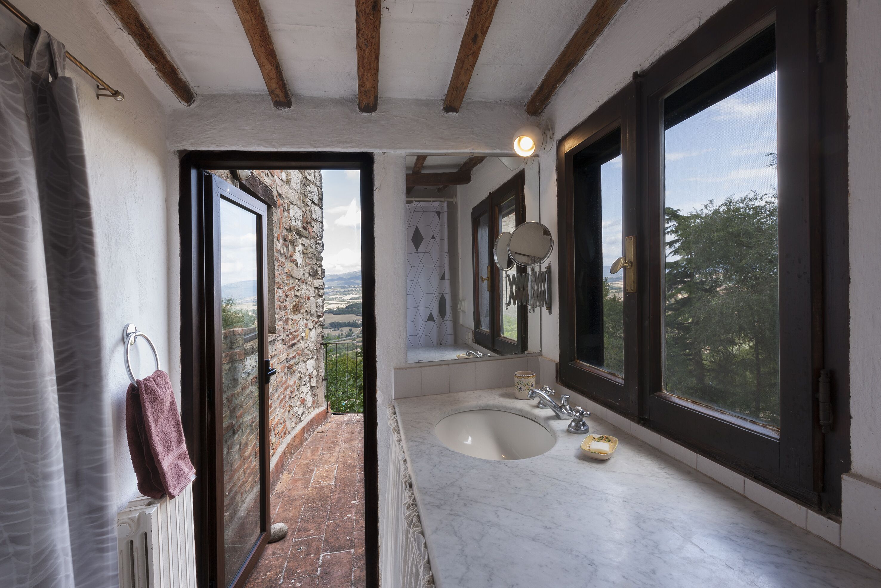 Un baño con un lavamanos grande, dos espejos y vistas al exterior.