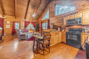 A wooden cabin interior with a dining area, kitchen, and a sofa. - ROMANTIC GETAWAY COZY CABIN (Cleveland)