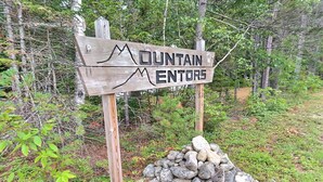 En träskylt med texten ”MOUNTAIN MENTORS” och en hög med stenar.