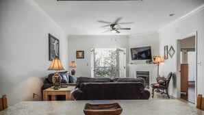 Ein Wohnzimmer mit Kamin, Deckenventilator und Wandfernseher.