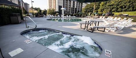 A hotel pool area with hot tubs, lounge chairs, and a picnic table.