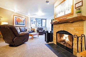 Ein Wohnzimmer mit Kamin, Ledersofa und großem Fenster.