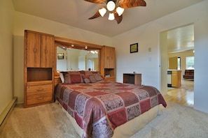 A bedroom with a large bed, wooden headboard, a ceiling fan, and a mirror above the bed. - Nice 1 bedroom easy access to pool/hot tub (Eden)