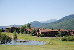 Un resort con varias edificaciones, un estanque y montañas al fondo.