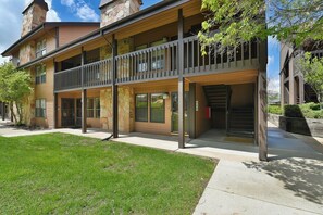 A two-story building with a balcony, large windows, and a garage entrance. - Nice 1 bedroom easy access to pool/hot tub (Eden)