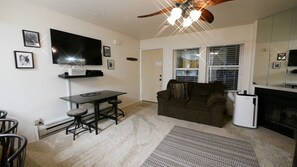 A living room with a flat-screen TV, a coffee table, a sofa, a fireplace, and a ceiling fan. - Nice 1 bedroom easy access to pool/hot tub (Eden)