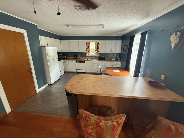 A kitchen with white cabinets, a wooden island, and a dining table.