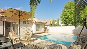 A pool area with lounge chairs and a table, surrounded by palm trees and a house with a tiled roof. - Pool house Close to the strip 3bedroom pool bungalow  (Las Vegas)