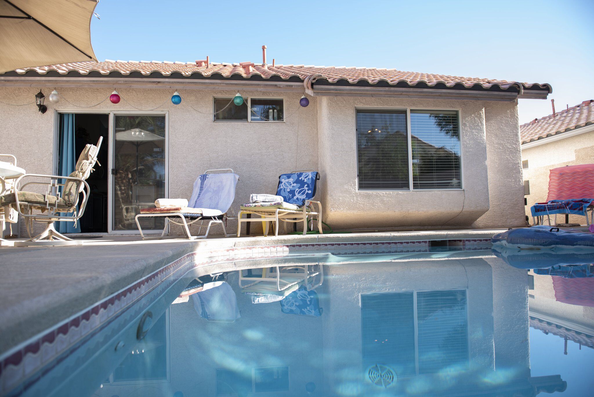 A swimming pool area with lounge chairs and a covered patio.