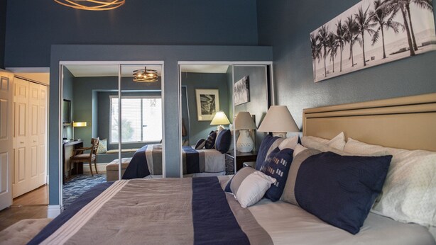 A bedroom with a large bed, bedside lamps, a desk, and a chair. There is a window with blinds and a door leading to another room. - Pool house Close to the strip 3bedroom pool bungalow  (Las Vegas)