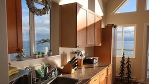 Una cucina con mobili in legno, un piano di lavoro in granito e vista mare.