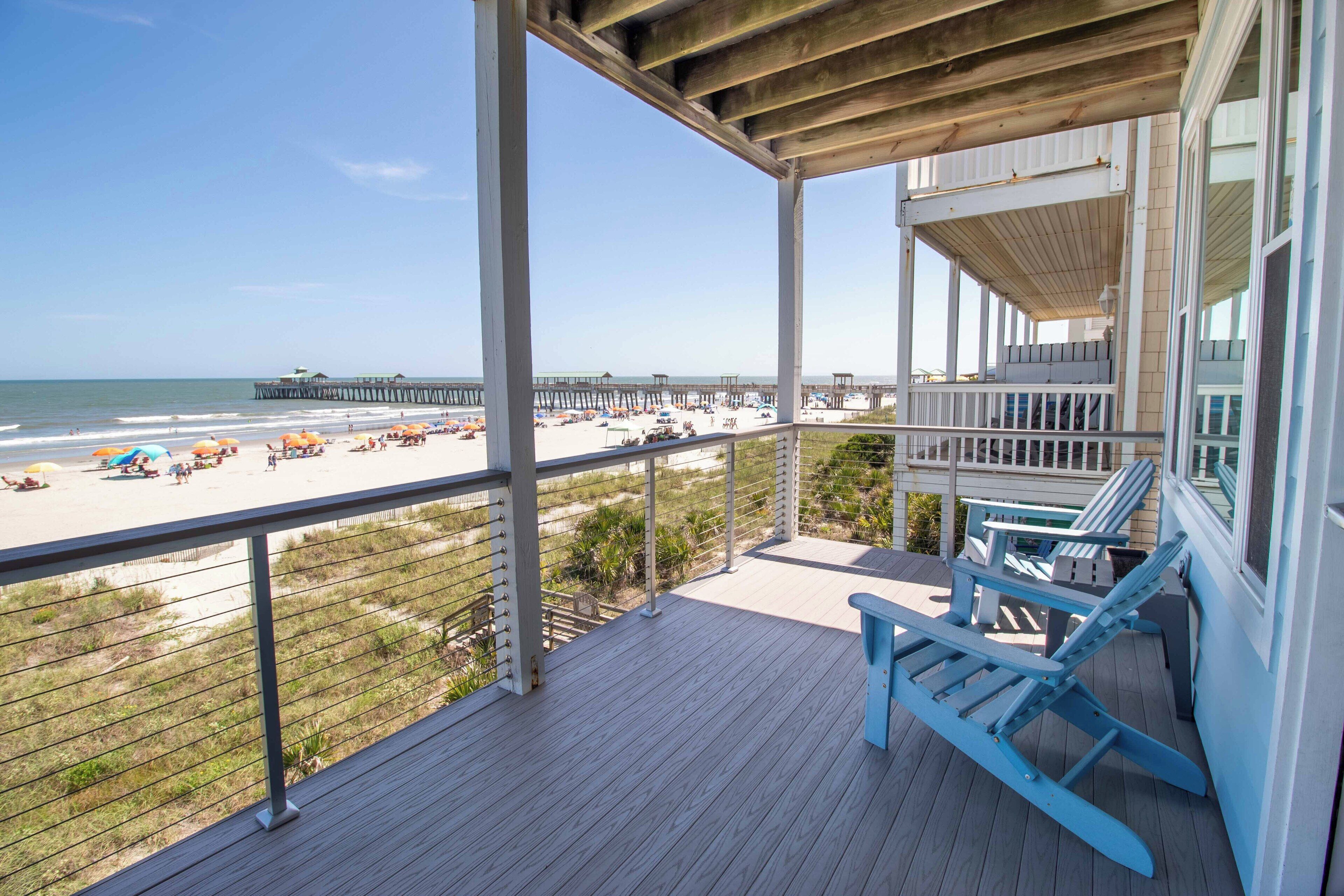 A wooden deck with a view of the beach and pier.