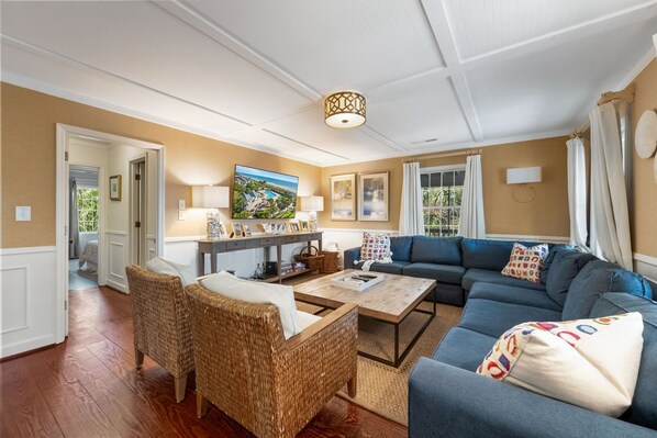 A living room with a blue sofa, wicker chairs, a coffee table, and a painting on the wall.