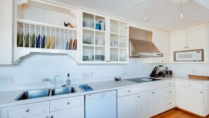 A modern kitchen with white cabinetry, a stainless steel sink, and a microwave. - Best Located Vacation Rental on all of Tybee Island (Tybee Island)