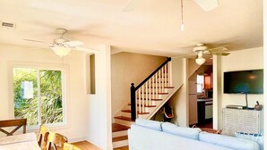 A spacious living area with a dining table, chairs, a light blue sofa, and two ceiling fans. - Best Located Vacation Rental on all of Tybee Island (Tybee Island)