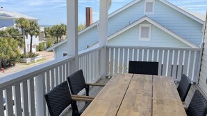 A wooden deck with a table and chairs, overlooking a residential area with houses and palm trees. - Best Located Vacation Rental on all of Tybee Island (Tybee Island)