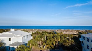 A coastal residential area with a view of the ocean, featuring modern houses, a beach, and a clear sky. - Best Located Vacation Rental on all of Tybee Island (Tybee Island)