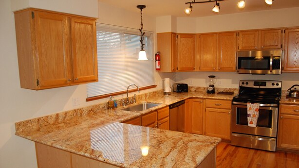 A kitchen with wooden cabinets, granite countertops, stainless steel appliances, and a built-in oven.