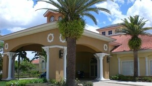 A building with a covered entrance, palm trees, and a clear sky. - Special rates available for Sep, Oct 2026 (Kissimmee)