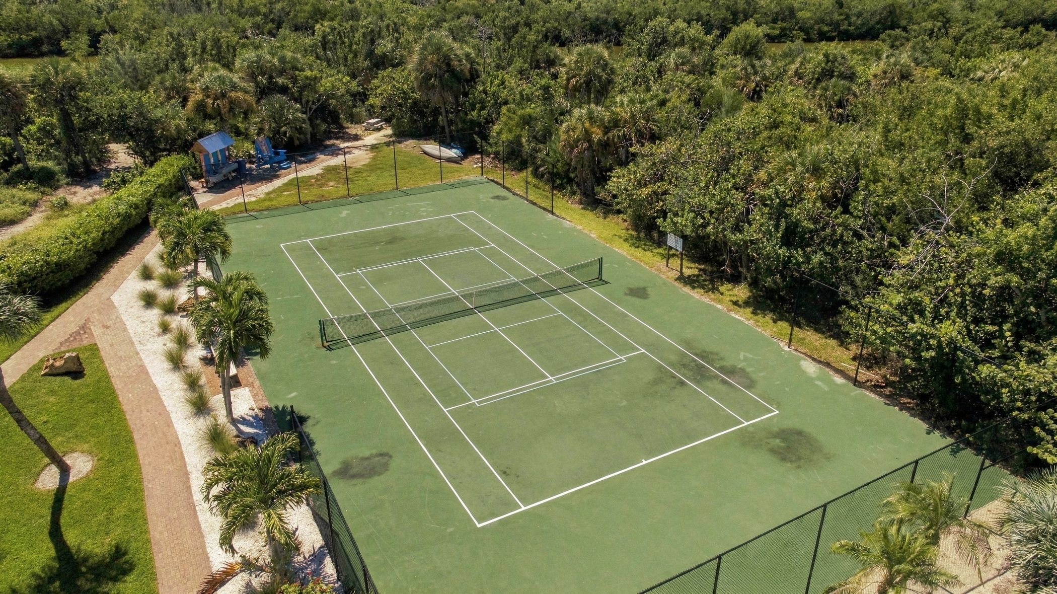 Ein Tennisplatz im Freien, umgeben von üppigem Grün.