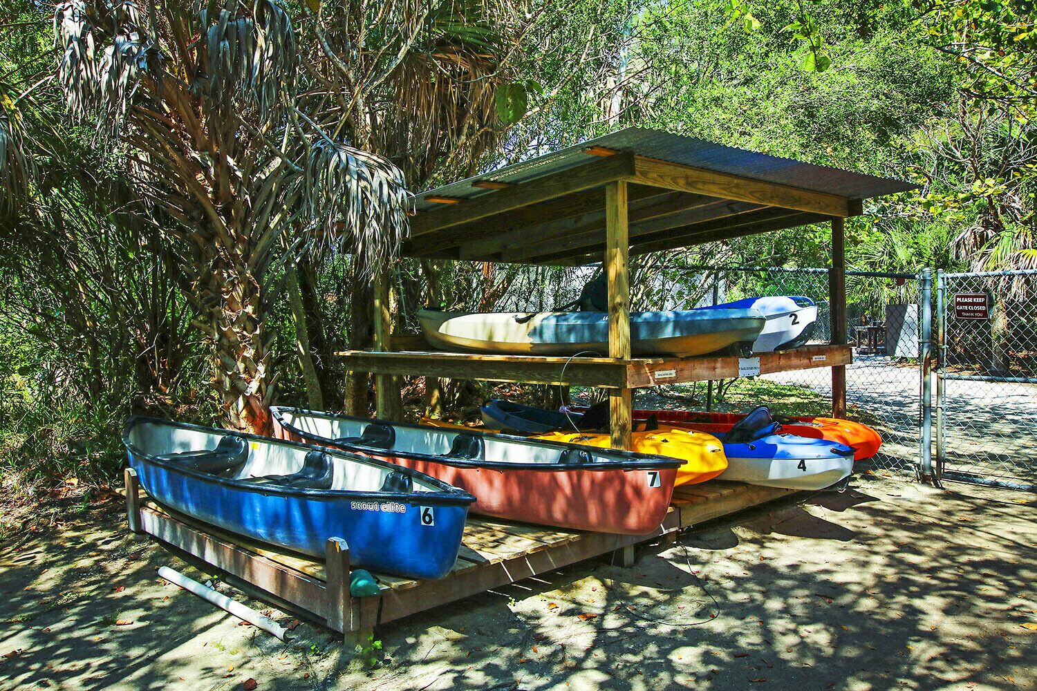 A covered boat rental area with multiple boats and a sign indicating a gate closure.