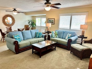 A living room with a sectional sofa, a coffee table, and a dining area with a table and chairs.